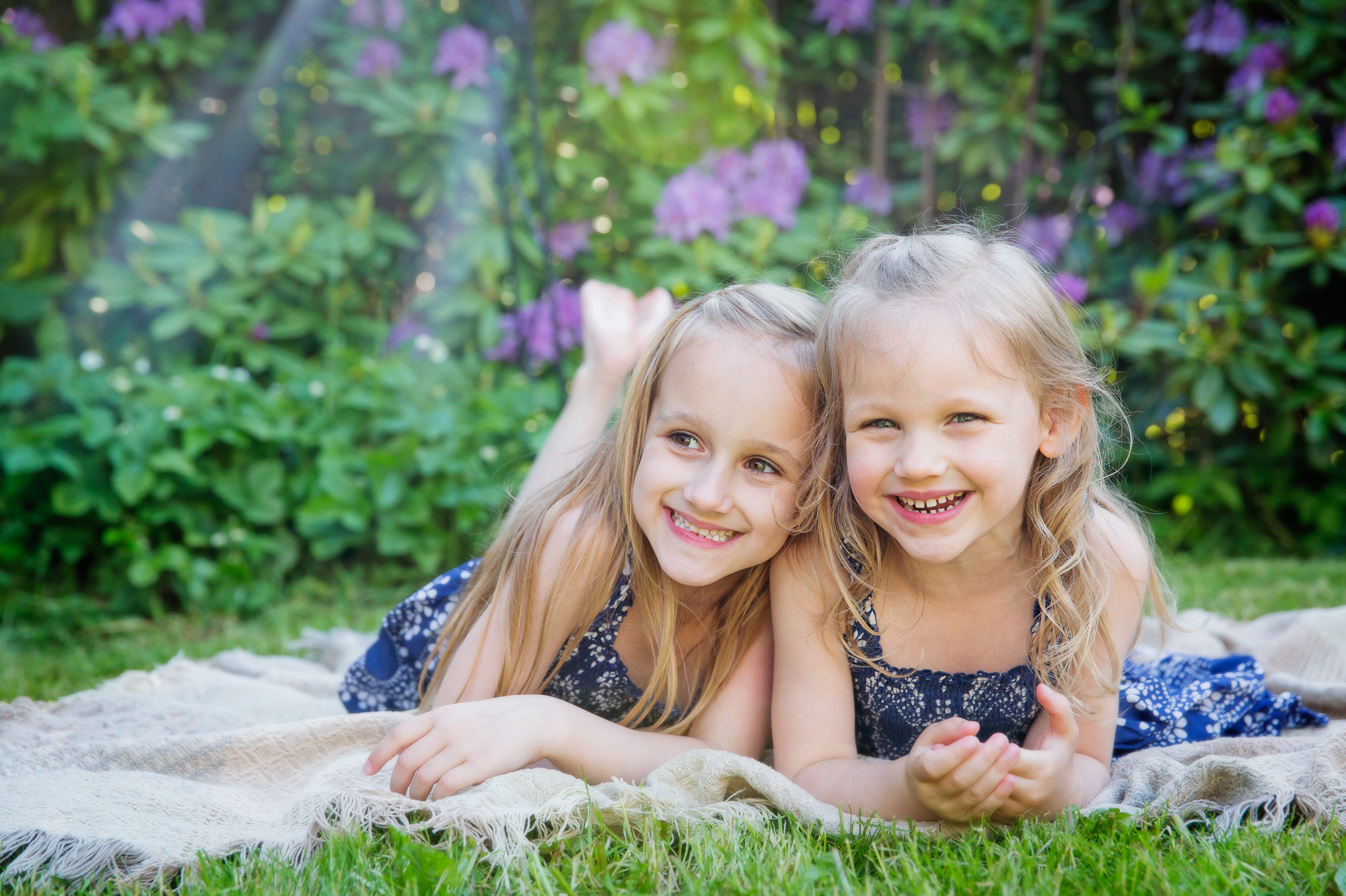 sisters laughing lying on a blanket in the garden